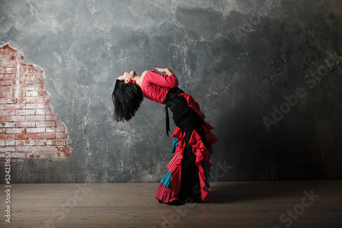 Young adult spanish woman dancing flamenco on gray vintage studio background