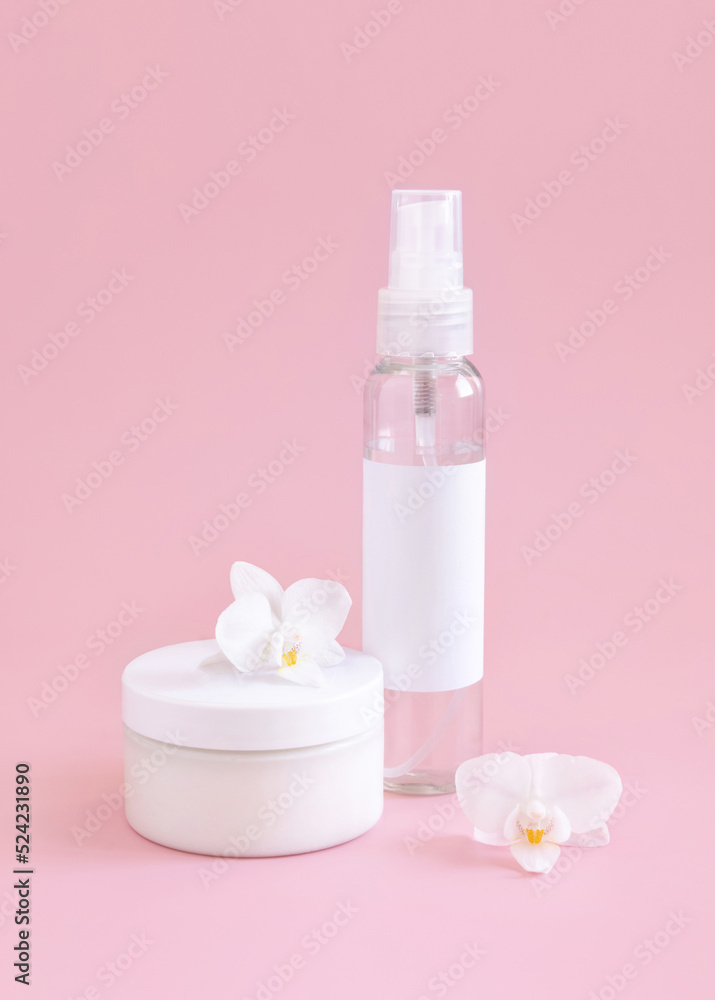 White cosmetic jar and bottle near white orchid flowers on light pink close up. Package Mockup