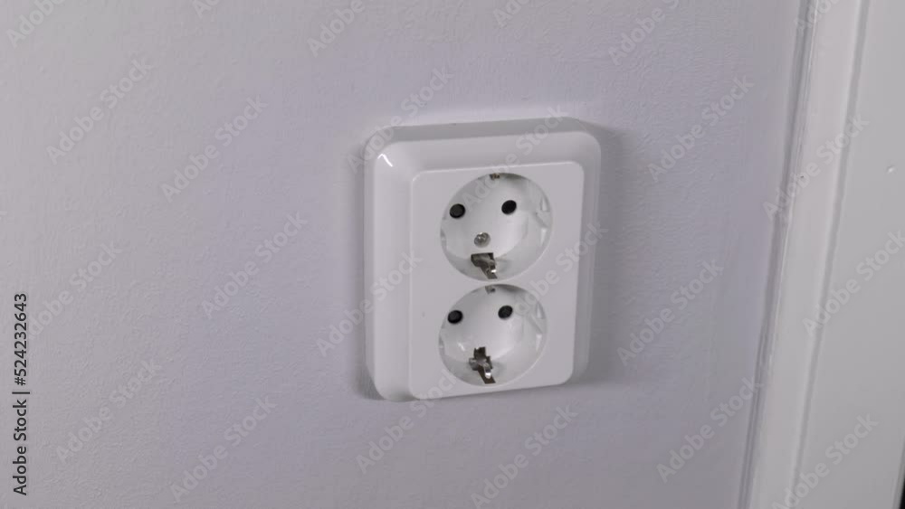 A man unplugging a cord from a wall socket, to help save energy and the