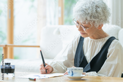 リビングで手紙を書くシニア女性
