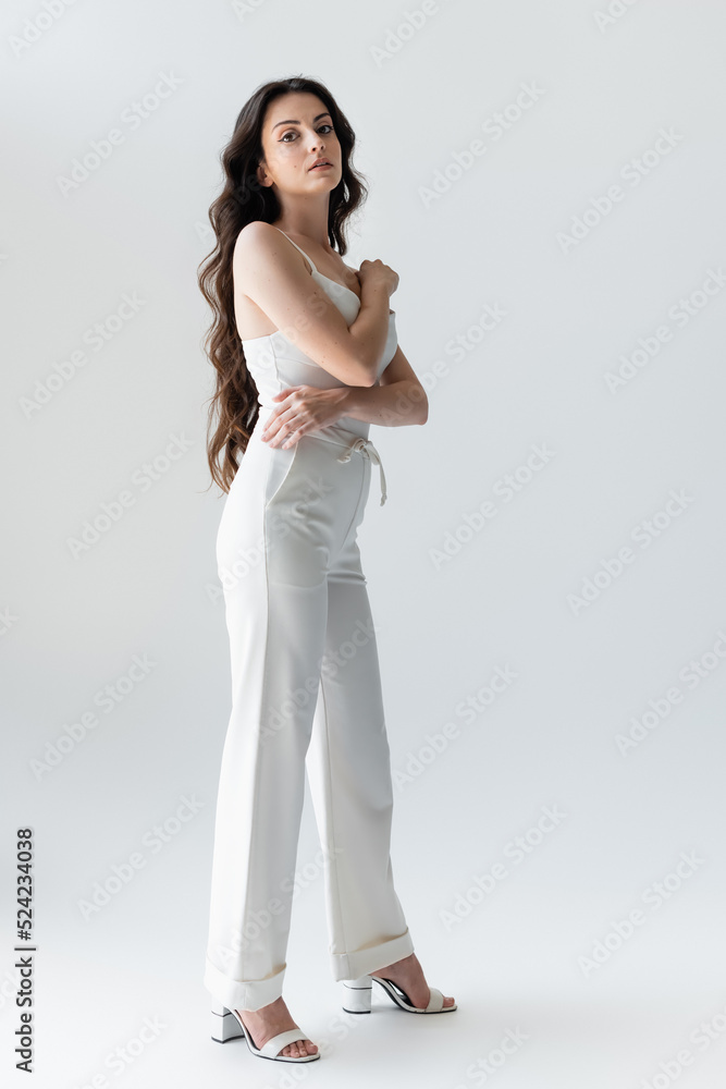 Full length of stylish long haired woman looking at camera on grey background. Full length of stylish long haired woman looking at camera on grey background.