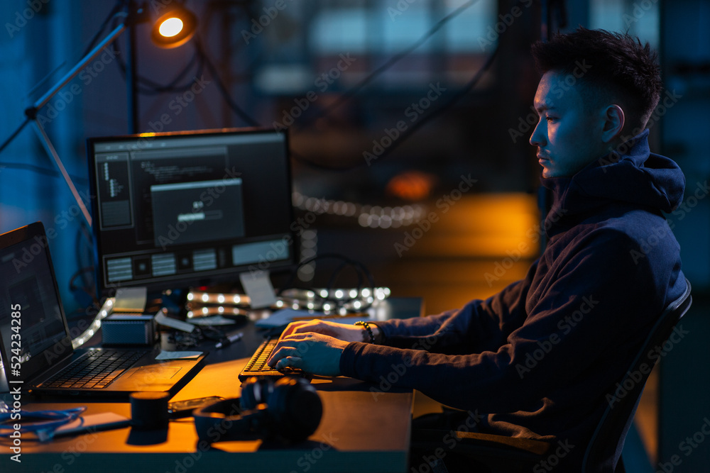 cybercrime, hacking and technology concept - male hacker in dark room writing code or using computer virus program for cyber attack cybercrime, hacking and technology concept - male hacker in dark room writing code or using computer virus program for cyber attack