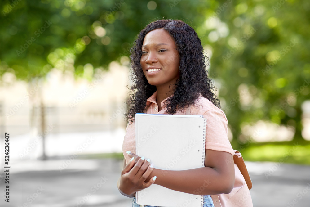 education, school and people concept - happy smiling african american student girl with notebooks in city education, school and people concept - happy smiling african american student girl with notebooks in city