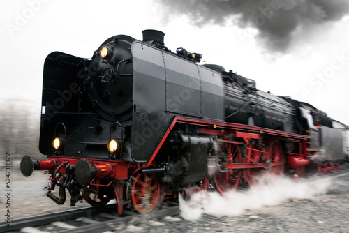 Eine Dampflokomotive spuckt Rauch und Dampf bei voller Fahrt mit wischeffekt durch Bewegungsunschärfe photo