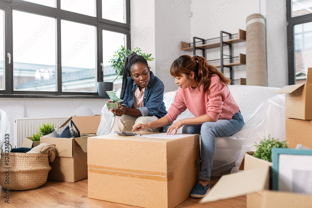 moving, finances and real estate concept - women with money, bills and calculator at new home moving, finances and real estate concept - women with money, bills and calculator at new home