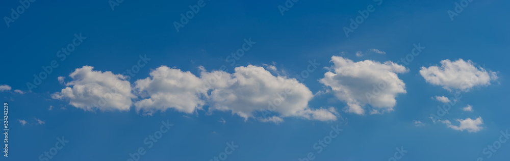 Small clouds are located on the same line against the sky.