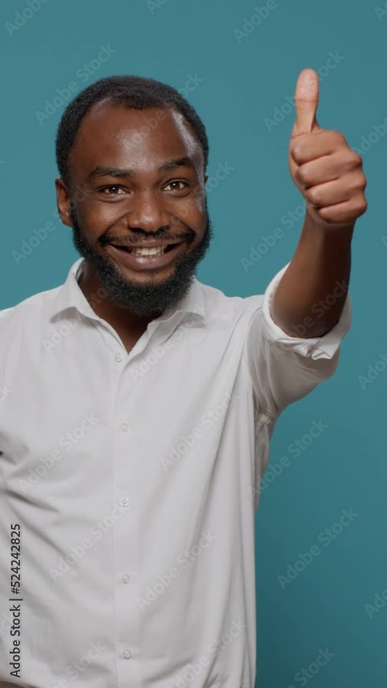 Vertical video: Optimistic person doing thumbs up gesture and approving idea, feeling positive and and satisfied. Confident man giving like to agree excellent solution, body language in studio. Vertical video: Optimistic person doing thumbs up gesture and approving idea, feeling positive and and satisfied. Confident man giving like to agree excellent solution, body language in studio.