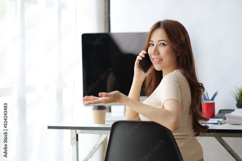 Portrait of an Asian woman working on a computer in the home office looking back at the camera. Portrait of an Asian woman working on a computer in the home office looking back at the camera.