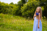 curly girl with blond hair walks in a field with flowers