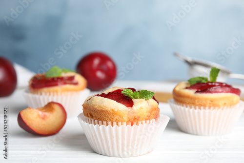 Delicious cupcakes with plums on white wooden table, closeup