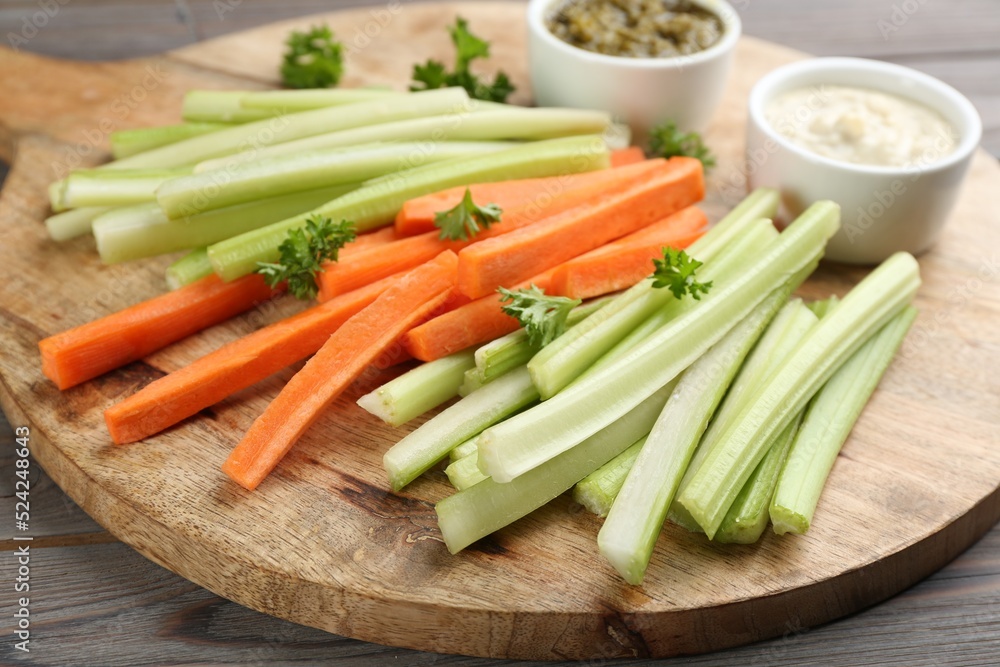Celery and other vegetable sticks with different sauces on wooden board Celery and other vegetable sticks with different sauces on wooden board