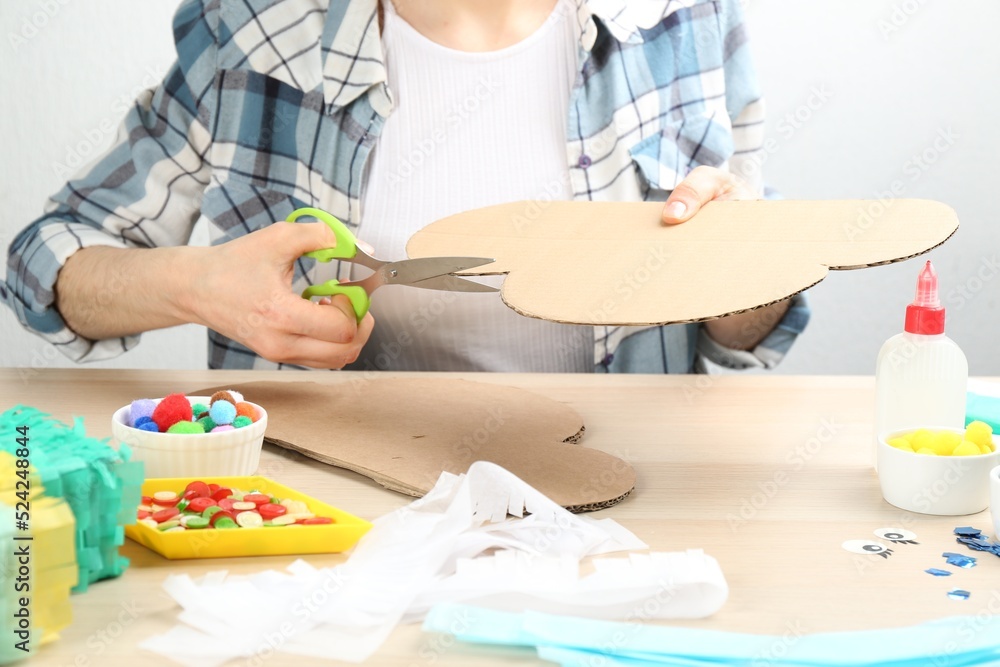 Woman making cardboard cloud at wooden table, closeup. Pinata diy Woman making cardboard cloud at wooden table, closeup. Pinata diy