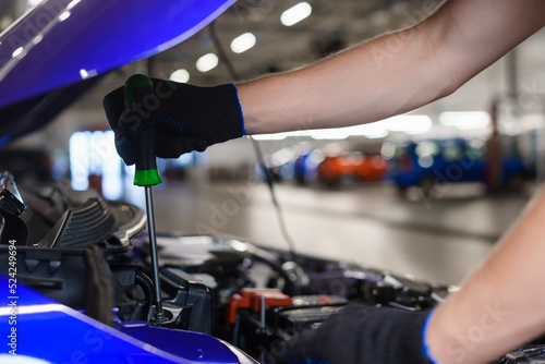 Close-up of a mechanic's hands with a screwdriver during repair work in a car service
