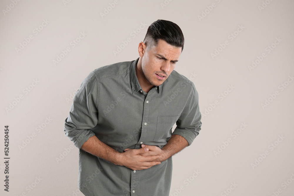 Man suffering from stomach ache on beige background. Food poisoning Man suffering from stomach ache on beige background. Food poisoning