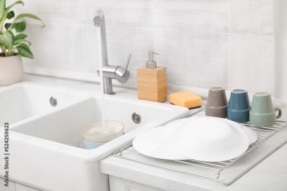 Drying rack with clean dishes near sink in stylish kitchen Drying rack with clean dishes near sink in stylish kitchen