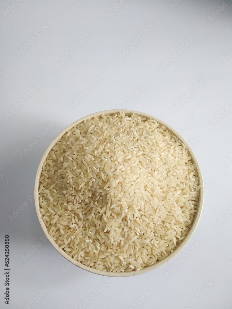 White raw rice in a bowl, on a white background top view White raw rice in a bowl, on a white background top view