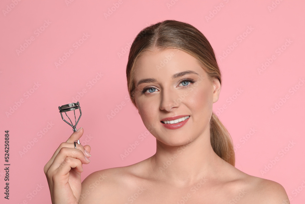 Young woman with eyelash curler on pink background Young woman with eyelash curler on pink background