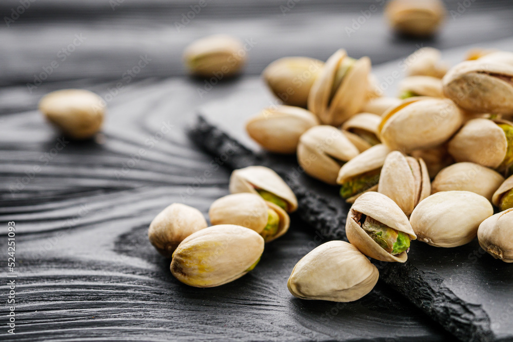 fresh salted pistachios on a black stone wooden rustic background