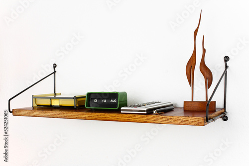 midcentury teak shelf on white wall in the living room with a wooden vase and a plack pen on it next to it a space age vintage orange lamp danish design front side low angle high view HIGH RESOLUTION photo