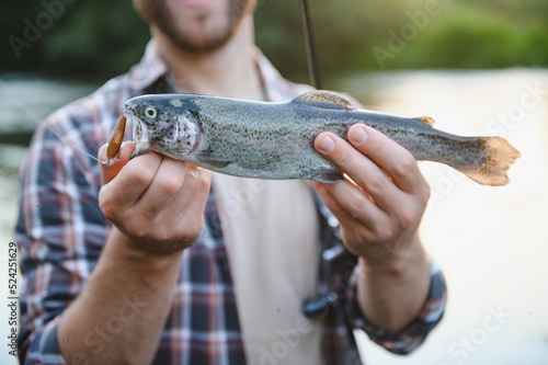 Happy fisherman holding a fish caught. Fishing on the beautiful river.