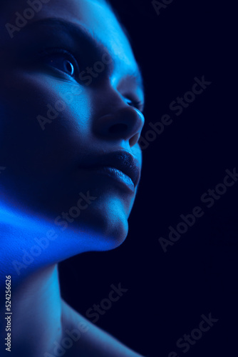 Marvelous night. Closeup portrait of young woman in neon light on dark background. Monochrome. Cyberpunk style, beauty, cosmetics concept.