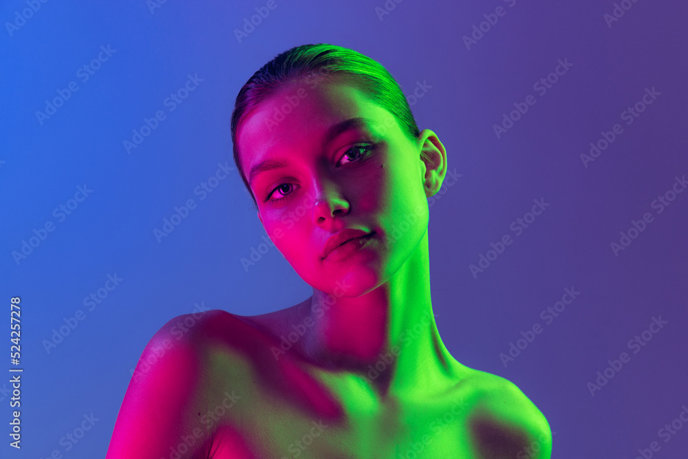Portrait of young, beautiful and healthy girl with well-kept skin isolated on dark background in neon light. Art, fashion, style, facial expression Portrait of young, beautiful and healthy girl with well-kept skin isolated on dark background in neon light. Art, fashion, style, facial expression