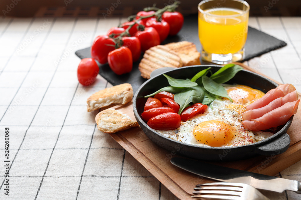 Delicious fried eggs with spinach, tomatoes and ham served on table. Space for text Delicious fried eggs with spinach, tomatoes and ham served on table. Space for text