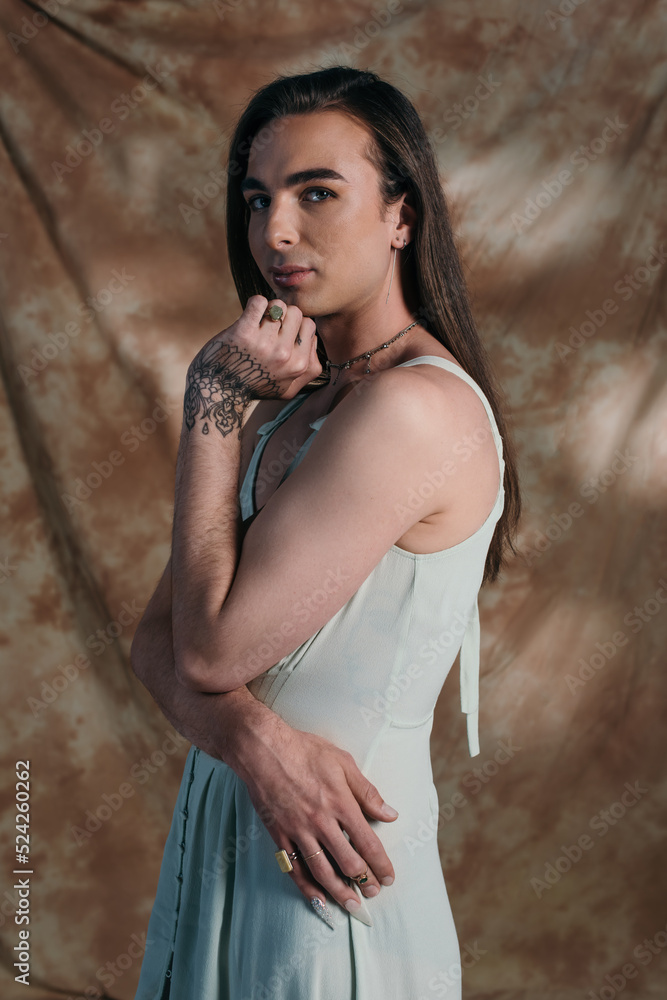 Naklejka premium Young queer person in sundress looking at camera on abstract background.