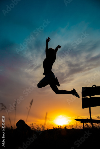 The silhouette of a child in a jump against the background of a beautiful sunset sky and a yellow sun © Ekaterina