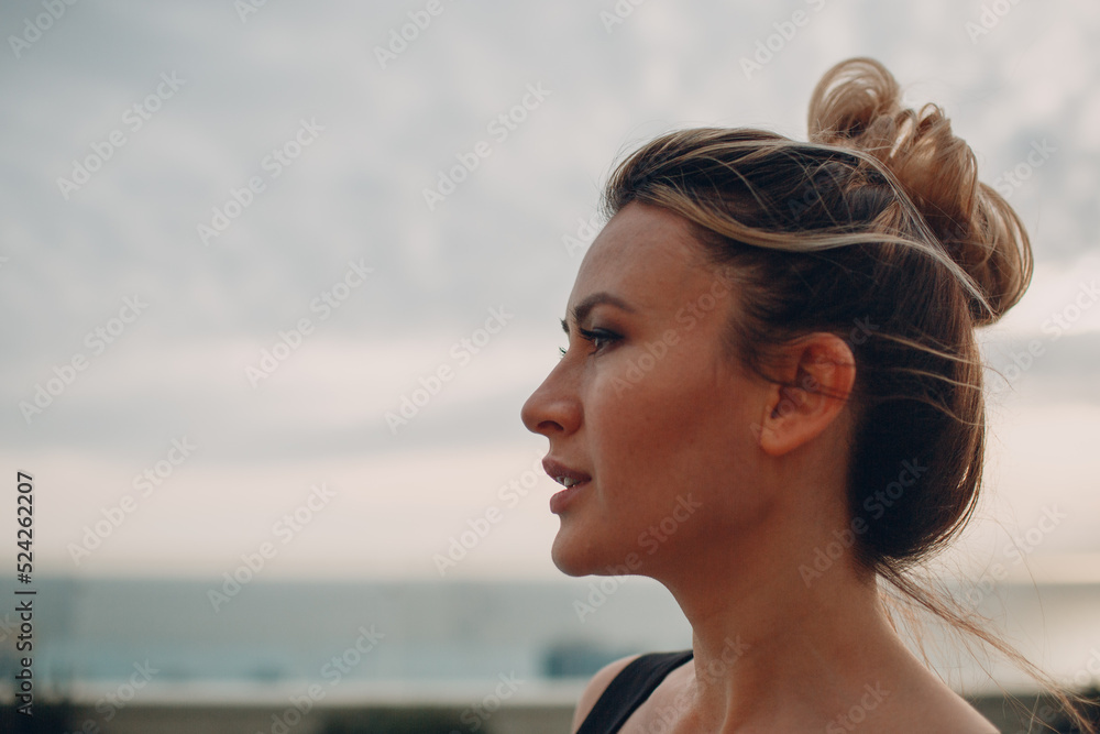 Young woman profile portrait standing against cloudy sky at pool Young woman profile portrait standing against cloudy sky at pool