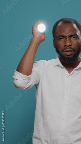 Vertical video: Confused person using flashlight to look for mysterous sound source, searching and examining around. Brave man taking risk and preparing for adventure in the dark with lantern. photo