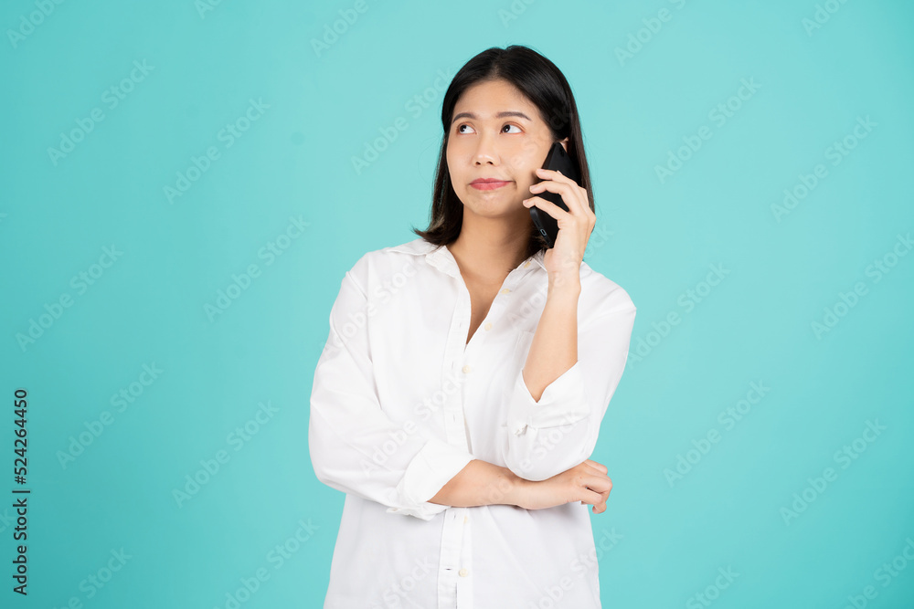 Portrait of a young woman using a smartphone and standing isolated on a bright green background. She had a suspicious look on her face. Portrait of a young woman using a smartphone and standing isolated on a bright green background. She had a suspicious look on her face.