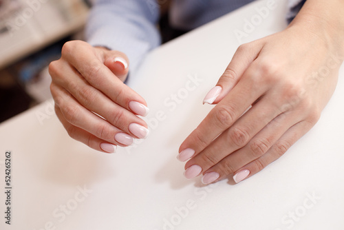 Female hand fingers nails with manicure after nail salon procedure.
