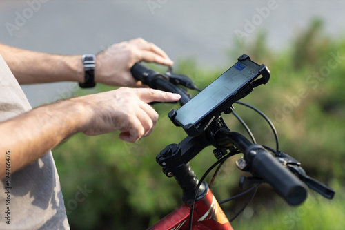 Man planning route pointing finger touch screen GPS navigation application in mobile phone on his bicycle bike