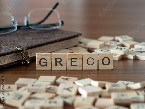 greco parola o concetto rappresentato da piastrelle di legno su un tavolo di legno con occhiali e un libro photo