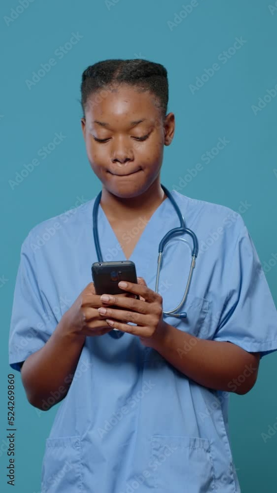 African american woman in uniform using smartphone to practice healthcare and medicine in studio. Medical assistant with stethoscope looking at mobile phone screen to do disease research African american woman in uniform using smartphone to practice healthcare and medicine in studio. Medical assistant with stethoscope looking at mobile phone screen to do disease research