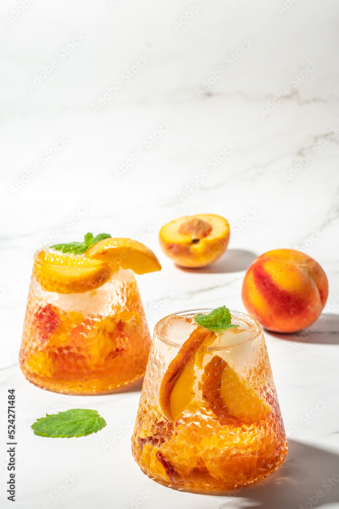homemade peach sangria with ice cubes, and mint, Refreshing summer homemade cocktails, on a light background, vertical image. top view. place for text