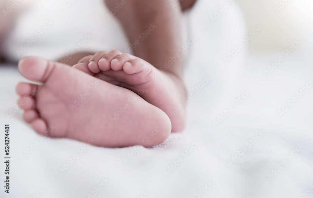 Closeup feet of newborn African black baby isolated on white hospital bed sheet. Healthcare and medical love lifestyle father or mother’s day background concept banner Closeup feet of newborn African black baby isolated on white hospital bed sheet. Healthcare and medical love lifestyle father or mother’s day background concept banner
