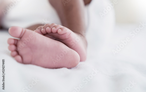 Closeup feet of newborn African black baby isolated on white hospital bed sheet. Healthcare and medical love lifestyle father or mother’s day background concept banner © paulaphoto