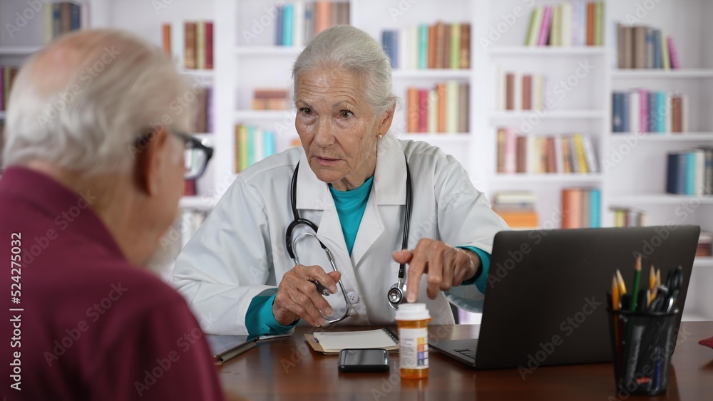 Serious old senior female general practitioner in lab coat holding digital computer tablet, showing laboratory test results to interested elderly 70s male patient at checkup meeting in hospital. Serious old senior female general practitioner in lab coat holding digital computer tablet, showing laboratory test results to interested elderly 70s male patient at checkup meeting in hospital.