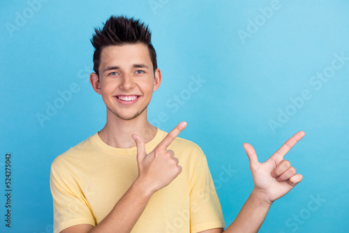 Bild auf Leinwand Portrait of young man in t-shirt pointing fingers away at copy space advert isol