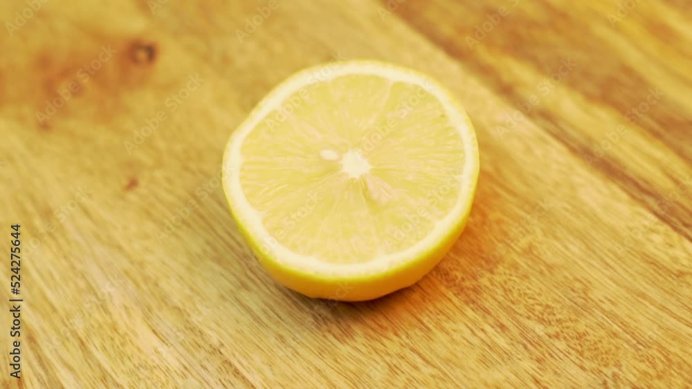 Half of a Juicy Lemon Spinning on a Wooden Surface, Close-up. Healthy Vitamin Vegan Food. Protecting the Immunity from Viral Infection Vitamin C. Half of a Juicy Lemon Spinning on a Wooden Surface, Close-up. Healthy Vitamin Vegan Food. Protecting the Immunity from Viral Infection Vitamin C.