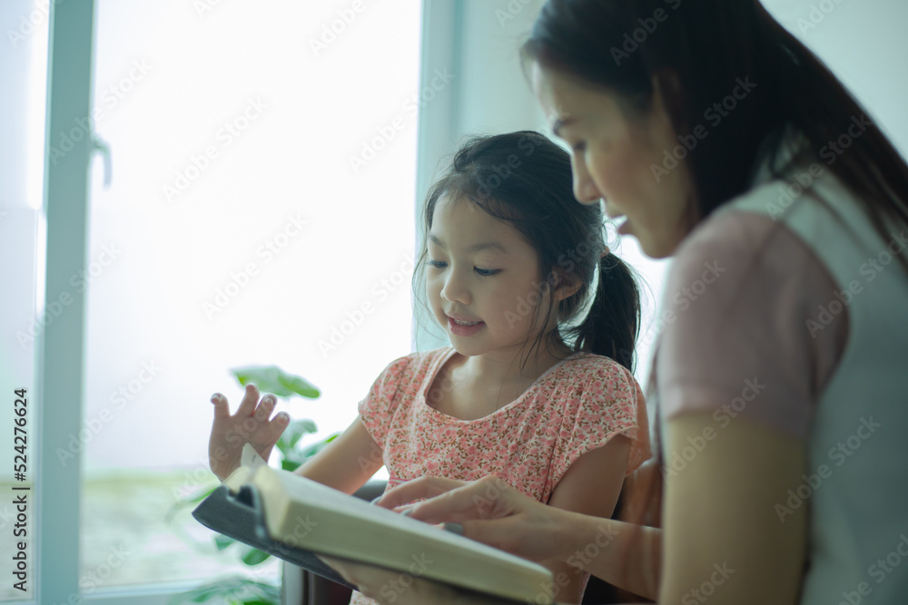 Mother and her daughter are reading a book and smiling on sofa. Mother and her daughter are reading a book and smiling on sofa.