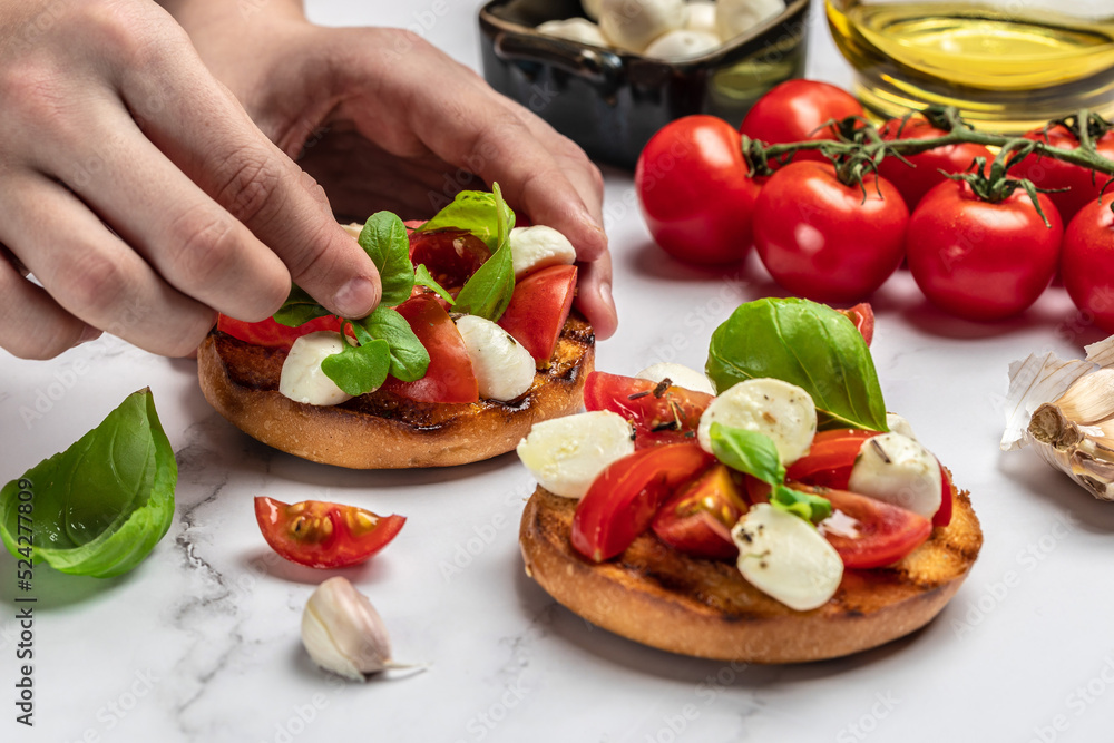 Woman hands preparing caprese bruschetta in the kitchen. Delicious breakfast or snack, Clean eating, dieting, vegan food concept. top view