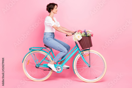 Full length photo of sweet pretty girl dressed white blouse driving bicycle looking empty space isolated pink color background © deagreez