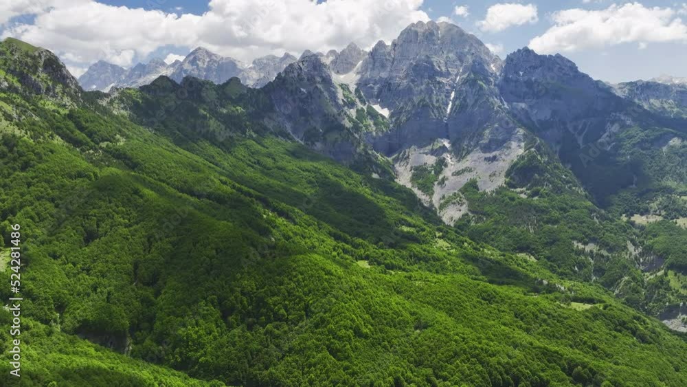 Aerial view of the Valbona river valley, green valleys, blue sky with clouds, steep rocks, remnants of snow. Hikers paradise. Theth national park, june, Albanian Alps, Albania. Aerial view of the Valbona river valley, green valleys, blue sky with clouds, steep rocks, remnants of snow. Hikers paradise. Theth national park, june, Albanian Alps, Albania.