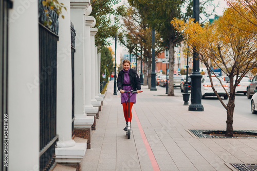 Young woman with electric scooter at the city. © primipil