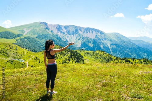 Young caucasian woman hold mini white alpine color drone in scenic nature mountains outdoors .Filmmaker shoot drone footage for commercial work outdoors