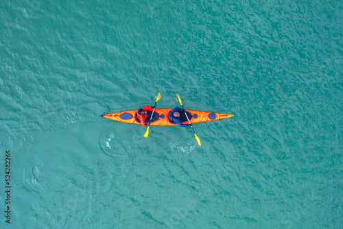 Foto Red kayak boat two rowers on blue turquoise water sea, sunny day