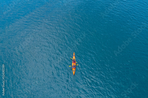 Red kayak boat two rowers on blue turquoise water sea, sunny day. Concept banner travel, aerial top view